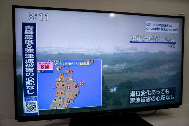 An advisory reading 'Intense tremors measuring upper 6 on the Japanese seismic scale hit Aomori. No risk of a tsunami.' is seen with the live footage of Fukushima Daiichi Nuclear Power Station, on a television screen in Kawasaki, Kanagawa prefecture on June 25, 2026. (Photo by Yuichi YAMAZAKI / AFP)