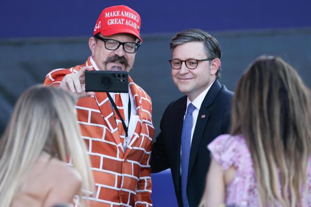 Blake Marnell, wearing a brick suit, takes a photo with US Speaker of the House Mike Johnson during a kick-off celebration for the "Great American State Fair" on the National Mall in Washington, DC, June 24, 2026. The "Great American State Fair" will be held from June 25 to July 10, 2026, to celebrate the 250th anniversary of US independence. (Photo by Jemal COUNTESS / AFP)
