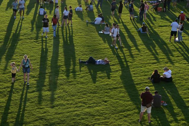 Attendees walk and sit on the grass during a kick-off celebration for the "Great American State Fair" on the National Mall in Washington, DC, June 24, 2026. The "Great American State Fair" will be held from June 25 to July 10, 2026, to celebrate the 250th anniversary of US independence. (Photo by Oliver Contreras / AFP)