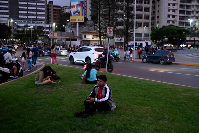 People remain in the street following an earthquake in Caracas on June 24, 2026. A magnitude 7.1 earthquake struck Venezuela on Wednesday, the United States Geological Survey (USGS) reported, triggering panic in Caracas, according to AFP journalists. The tremor, which was followed by several aftershocks, was also felt in Colombia. (Photo by Federico PARRA / AFP)