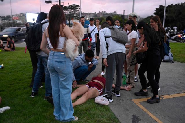 A woman lies on the ground while being assisted in the street following an earthquake in Caracas on June 24, 2026. A magnitude 7.1 earthquake struck Venezuela on Wednesday, the United States Geological Survey (USGS) reported, triggering panic in Caracas, according to AFP journalists. The tremor, which was followed by several aftershocks, was also felt in Colombia. (Photo by Federico PARRA / AFP)
