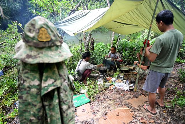 This photo taken on June 10, 2026 shows rangers and local community members eating breakfast in the Cardamom National Park in Koh Kong province. Above the patter of rain cascading through the jungle canopy comes the haunting call of a pileated gibbon singing to fend off intruders in Cambodia's Cardamom Mountains. (Photo by TANG CHHIN Sothy / AFP) / To go with 'CAMBODIA-CONSERVATION-ENVIRONMENT-ANIMAL-SCIENCE-FORESTS,FOCUS' by Sara HUSSEIN and Suy SE