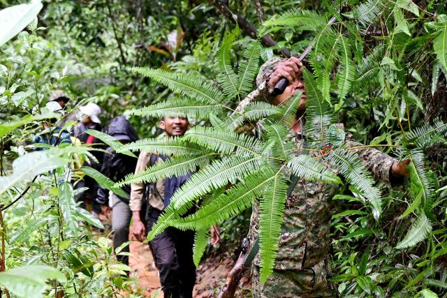 This photo taken on June 9, 2026 shows ranger Hou Sophoan clearing his way in the jungle in the Cardamom National Park in Koh Kong province. Above the patter of rain cascading through the jungle canopy comes the haunting call of a pileated gibbon singing to fend off intruders in Cambodia's Cardamom Mountains. (Photo by TANG CHHIN Sothy / AFP) / To go with 'CAMBODIA-CONSERVATION-ENVIRONMENT-ANIMAL-SCIENCE-FORESTS,FOCUS' by Sara HUSSEIN and Suy SE