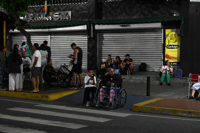 People remain in the street following an earthquake in Caracas on June 24, 2026. Two earthquakes of magnitude 7.2 and 7.5 struck the same area of Venezuela on the evening of June 24, causing buildings to collapse, according to the United States Geological Survey (USGS) and AFP journalists. The quakes drove residents of the capital, Caracas, into the streets. (Photo by Juan BARRETO / AFP)