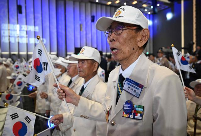 South Korean war veterans wave national flags during a ceremony marking the 76th anniversary of the outbreak of the Korean War in Suwon on June 25, 2026. (Photo by Jung Yeon-je / AFP)