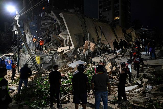 Rescuers search through the rubble of a collapsed building in the Altamira neighbourhood following an earthquake in Caracas on June 24, 2026. Two earthquakes of magnitude 7.2 and 7.5 struck the same area of Venezuela on the evening of June 24, causing buildings to collapse, according to the United States Geological Survey (USGS) and AFP journalists. The quakes drove residents of the capital, Caracas, into the streets. (Photo by Federico PARRA / AFP)