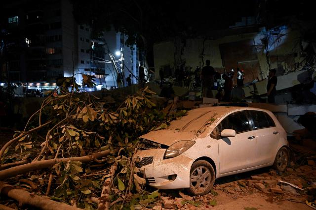 A car crushed by a fallen tree is seen following an earthquake in Caracas on June 24, 2026. Two earthquakes of magnitude 7.2 and 7.5 struck the same area of Venezuela on the evening of June 24, causing buildings to collapse, according to the United States Geological Survey (USGS) and AFP journalists. The quakes drove residents of the capital, Caracas, into the streets. (Photo by Federico PARRA / AFP)