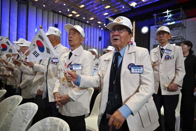 South Korean war veterans wave national flags during a ceremony marking the 76th anniversary of the outbreak of the Korean War in Suwon on June 25, 2026. (Photo by Jung Yeon-je / AFP)