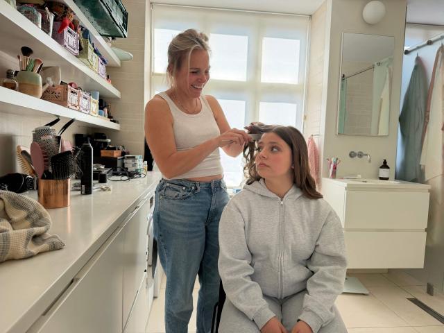 Nora Pihl, a 15-year-old Dane gets her hair done by her mother Anne Pihl on May 23, 2026 in Copenhagen to be ready before having a “humanist” confirmation. At 15, like most Danish teenagers, Nora Pihl chose to get confirmed but for her, as for a growing number of young Danes, it wasn't a religious affair. Confirmation is a rite in many Christian churches where someone who has already been baptised professes their faith, thereby confirming their baptism. Confirmation in Denmark's national Evangelical Lutheran Church was mandatory to obtain an identity card, work, or get married, and the ritual became firmly rooted in Danish culture. (Photo by Camille BAS-WOHLERT / AFP)
