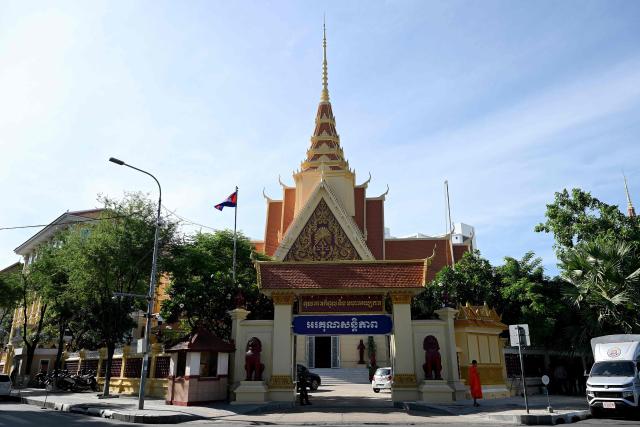 A Cambodian Buddhist monk (R) stands in front of the Supreme Court in Phnom Penh on June 25, 2026. Cambodia's Supreme Court on June 25 upheld 14-year prison sentences for two journalists convicted of treason for posting a photo taken in a military-restricted area after a round of border clashes with Thailand, a judge told AFP. (Photo by TANG CHHIN Sothy / AFP)