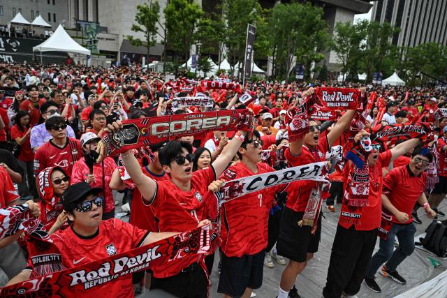 South Korean fans cheer as they watch the 2026 World Cup football match between South Korea and South Africa on big screens at Gwanghwamun Square in Seoul on June 25, 2026. (Photo by Jade GAO / AFP)