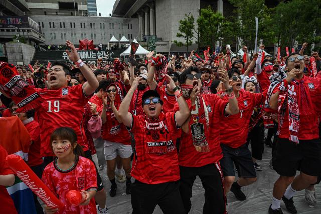 South Korean fans react as they watch the 2026 World Cup football match between South Korea and South Africa on big screens at Gwanghwamun Square in Seoul on June 25, 2026. (Photo by Jade GAO / AFP)
