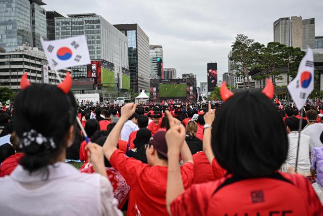 South Korean fans react as they watch the 2026 World Cup football match between South Korea and South Africa on big screens at Gwanghwamun Square in Seoul on June 25, 2026. (Photo by Jade GAO / AFP)