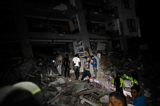 Residents and emergency workers stand in the rubble near damaged buildings following an earthquake in Catia La Mar, La Guaira state, some 30kms north-west of Caracas, early on June 25, 2026. Powerful twin earthquakes have killed 32 people and injured more than 700, the nation's interim president said on June 25, after the massive shocks collapsed entire buildings and sent people running in panic. (Photo by Federico PARRA / AFP)