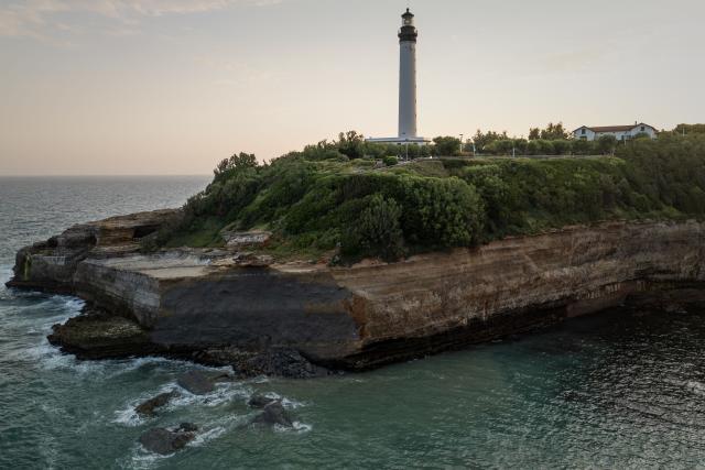 This aerial photograph shows the cliff facing Miramar beach, below the Biarritz lighthouse, on the morning after a cliff collapse, in Biarritz, south-western France, on June 25, 2026. A section of cliff approximately 2,000 square metres in size fell into the sea on the evening of June 24. The body of one victim was found, authorities said shortly before 11 pm, while another person was still missing. (Photo by Philippe LOPEZ / AFP)