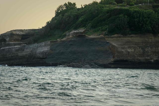 This photograph shows a fresh rockfall scar of the cliff facing Miramar beach, below the Biarritz lighthouse, on the morning after it collapsed, in Biarritz, south-western France, on June 25, 2026. A section of cliff approximately 2,000 square metres in size fell into the sea on the evening of June 24. The body of one victim was found, authorities said shortly before 11 pm, while another person was still missing. (Photo by Philippe LOPEZ / AFP)