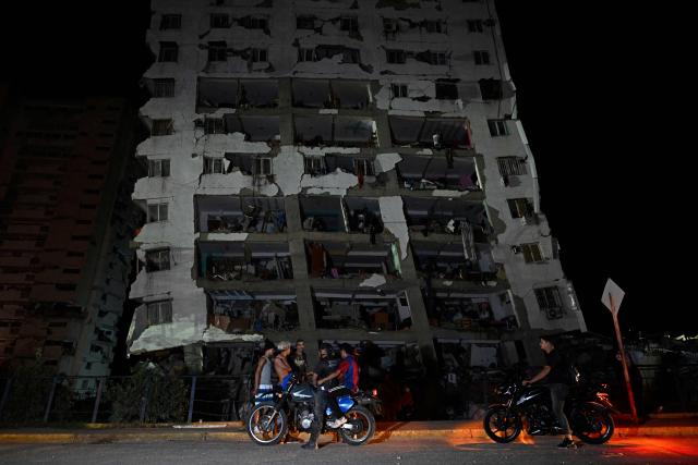 People gather outside a damaged building following an earthquake in Catia La Mar, La Guaira state, some 30kms north-west of Caracas, early on June 25, 2026. Powerful twin earthquakes have killed 32 people and injured more than 700, the nation's interim president said on June 25, after the massive shocks collapsed entire buildings and sent people running in panic. (Photo by Federico PARRA / AFP)