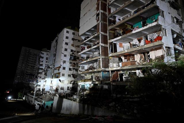 People walk past damaged building following an earthquake in Catia La Mar, La Guaira state, some 30kms north-west of Caracas, early on June 25, 2026. Powerful twin earthquakes have killed 32 people and injured more than 700, the nation's interim president said on June 25, after the massive shocks collapsed entire buildings and sent people running in panic. (Photo by Federico PARRA / AFP)