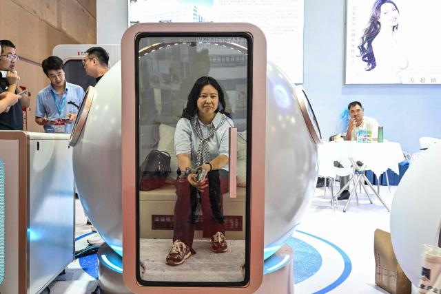 A woman is seen inside a micro hyperbaric oxygen chamber during the 2026 Shanghai International Medical Devices Exhibition in Shanghai on June 25, 2026. (Photo by HECTOR RETAMAL / AFP)