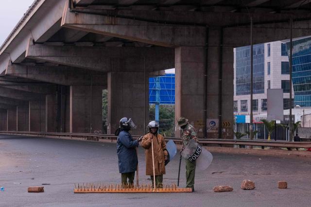 Kenyan police officers stand at a roadblock near the Kangemi bridge ahead of the planned demonstrations to mark the second anniversary of the deadly June 2024 youth-led anti-Finance Bill protests, which saw demonstrators storm Parliament, in Nairobi on June 25, 2026. Thousands of Kenyans protested in June 2024 against economic hardship and corruption, eventually storming parliament to force the cancellation of new taxes. (Photo by Kabir DHANJI / AFP)