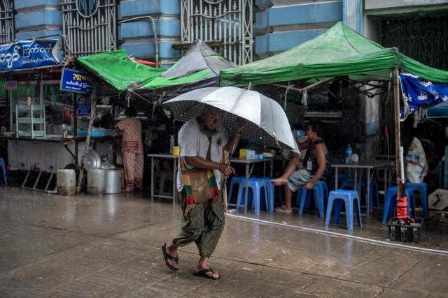 A man walks with an umbrella to shield himself during heavy rain in Yangon on June 25, 2026. (Photo by Sai Aung MAIN / AFP)