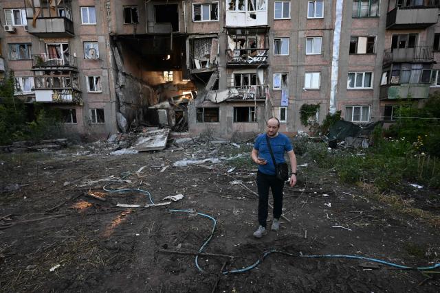 A man walks in front of a heavily damaged multi-storey apartment building following a recent attack, which local Russian-installed officials called a Ukrainian drone strike, in the town of Gorlivka in the Donetsk region, Russian-controlled Ukraine, on June 24, 2026, amid the ongoing Russian-Ukrainian conflict. (Photo by AFP)