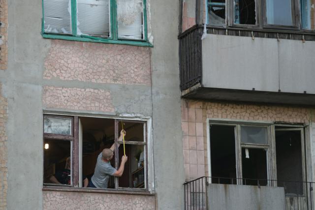 A man measures the window in a heavily damaged multi-storey apartment building following a recent attack, which local Russian-installed officials called a Ukrainian drone strike, in the town of Gorlivka in the Donetsk region, Russian-controlled Ukraine, on June 24, 2026, amid the ongoing Russian-Ukrainian conflict. (Photo by AFP)