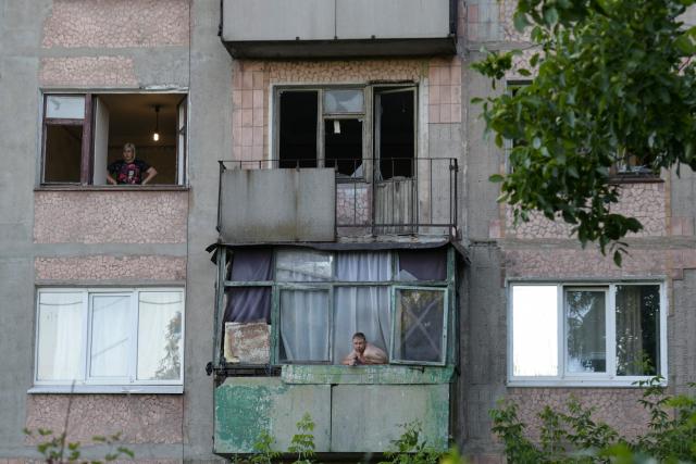 A man smokes at a balcony of a heavily damaged multi-storey apartment building following a recent attack, which local Russian-installed officials called a Ukrainian drone strike, in the town of Gorlivka in the Donetsk region, Russian-controlled Ukraine, on June 24, 2026, amid the ongoing Russian-Ukrainian conflict. (Photo by AFP)