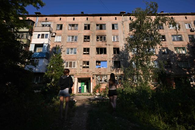 Girls look at a heavily damaged multi-storey apartment building following a recent attack, which local Russian-installed officials called a Ukrainian drone strike, in the town of Gorlivka in the Donetsk region, Russian-controlled Ukraine, on June 24, 2026, amid the ongoing Russian-Ukrainian conflict. (Photo by AFP)