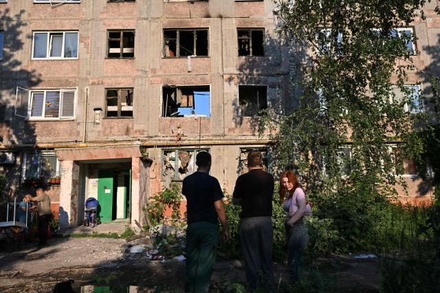 Youths stand in front of a heavily damaged multi-storey apartment building following a recent attack, which local Russian-installed officials called a Ukrainian drone strike, in the town of Gorlivka in the Donetsk region, Russian-controlled Ukraine, on June 24, 2026, amid the ongoing Russian-Ukrainian conflict. (Photo by AFP)