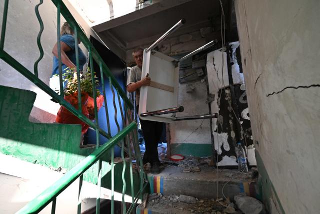Residents take belongings off a heavily damaged multi-storey apartment building following a recent attack, which local Russian-installed officials called a Ukrainian drone strike, in the town of Gorlivka in the Donetsk region, Russian-controlled Ukraine, on June 24, 2026, amid the ongoing Russian-Ukrainian conflict. (Photo by AFP)