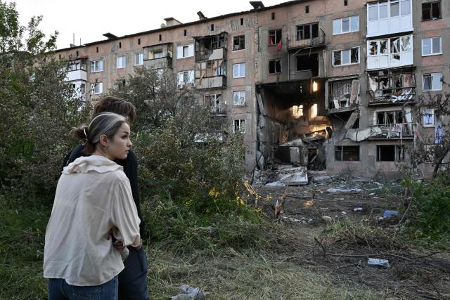 Youths react in front of a heavily damaged multi-storey apartment building following a recent attack, which local Russian-installed officials called a Ukrainian drone strike, in the town of Gorlivka in the Donetsk region, Russian-controlled Ukraine, on June 24, 2026, amid the ongoing Russian-Ukrainian conflict. (Photo by AFP)