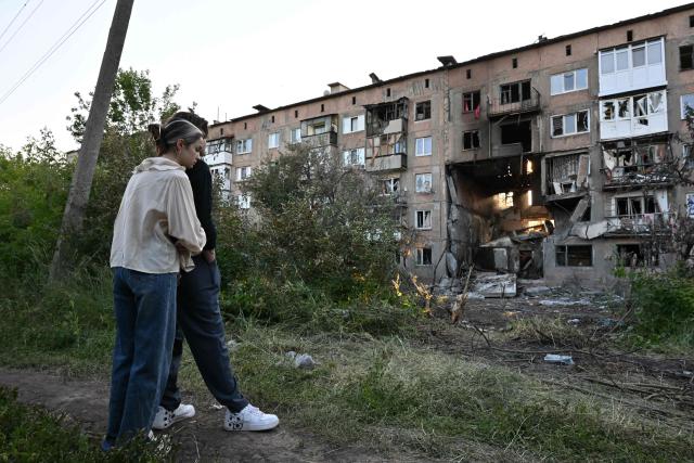 Youths react in front of a heavily damaged multi-storey apartment building following a recent attack, which local Russian-installed officials called a Ukrainian drone strike, in the town of Gorlivka in the Donetsk region, Russian-controlled Ukraine, on June 24, 2026, amid the ongoing Russian-Ukrainian conflict. (Photo by AFP)