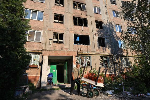 A resident takes belongings off a heavily damaged multi-storey apartment building following a recent attack, which local Russian-installed officials called a Ukrainian drone strike, in the town of Gorlivka in the Donetsk region, Russian-controlled Ukraine, on June 24, 2026, amid the ongoing Russian-Ukrainian conflict. (Photo by AFP)