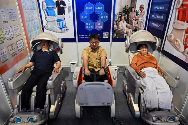 People receive a massage during the Shanghai International Medical Devices Exhibition in Shanghai on June 25, 2026. (Photo by HECTOR RETAMAL / AFP)