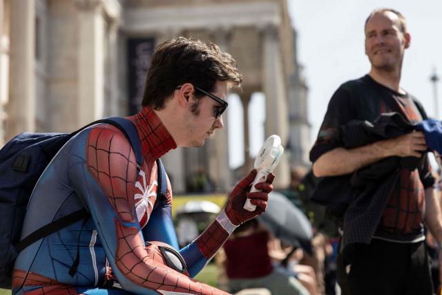 A Spider-man fan (L) in costume tries to cool off in the heat while waiting for a promotional event for the upcoming premiere of the film "Spider-Man: Brand New Day", in central London on June 25, 2026. (Photo by Brook Mitchell / AFP)
