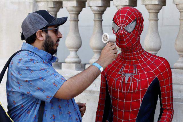 A Spider-man fan (R) in costume tries to cool off in the heat while waiting for a promotional event for the upcoming premiere of the film "Spider-Man: Brand New Day", in central London on June 25, 2026. (Photo by Brook Mitchell / AFP)