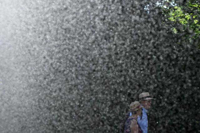 A man and woman walk past the water stream of a sprinkler system at the WTA 500 Bad Homburg Open tennis tournament in Bad Homburg, western Germany on June 25, 2026. (Photo by Kirill KUDRYAVTSEV / AFP)