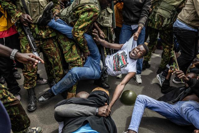A protester reacts while being arrested by Kenyan police officers outside Parliament buildings during demonstrations marking the second anniversary of the deadly June 2024 youth-led anti-Finance Bill protests, which saw demonstrators storm Parliament, in Nairobi on June 25, 2026. Kenyan police put on a massive show of force on June 26 in a bid to prevent protests marking two years since a landmark Gen Z uprising. Thousands of Kenyans took to the streets in June 2024 against economic hardship and corruption, eventually storming parliament to force the cancellation of new taxes. (Photo by Luis TATO / AFP)
