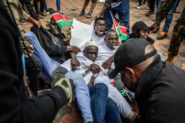 Protesters react as they try to resist while being arrested by Kenyan police officers outside Parliament buildings during demonstrations marking the second anniversary of the deadly June 2024 youth-led anti-Finance Bill protests, which saw demonstrators storm Parliament, in Nairobi on June 25, 2026. Kenyan police put on a massive show of force on June 25 in a bid to prevent protests marking two years since a landmark Gen Z uprising. Thousands of Kenyans took to the streets in June 2024 against economic hardship and corruption, eventually storming parliament to force the cancellation of new taxes. (Photo by Luis TATO / AFP)