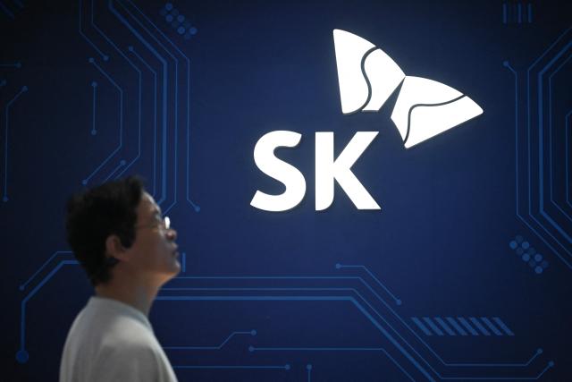 A woman walks past a logo of the SK Group booth during the China International Supply Chain Expo (CISCE) in Beijing on June 25, 2026. (Photo by Pedro PARDO / AFP)