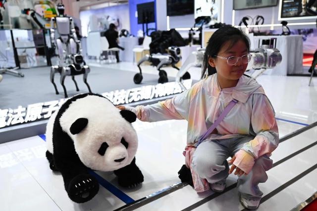 A girl poses for a picture next to a panda robot during the China International Supply Chain Expo (CISCE) in Beijing on June 25, 2026. (Photo by Pedro PARDO / AFP)