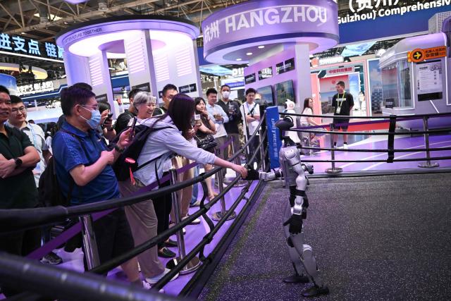 An exhibition humanoid robot from Unitree shakes hands with a visitor during the China International Supply Chain Expo (CISCE) in Beijing on June 25, 2026. (Photo by Pedro PARDO / AFP)