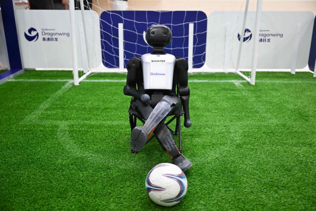 The Booster humanoid robot, a football player, is displayed at the Qualcomm booth during the China International Supply Chain Expo (CISCE) in Beijing on June 25, 2026. (Photo by Pedro PARDO / AFP)