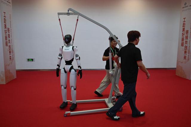 Workers move a Ubtech humanoid robot during the China International Supply Chain Expo (CISCE) in Beijing on June 25, 2026. (Photo by Pedro PARDO / AFP)