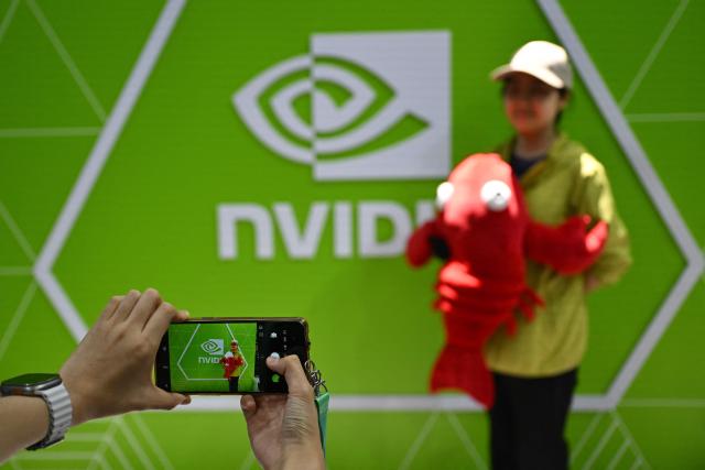 A woman poses for a picture at the NVIDIA booth during the China International Supply Chain Expo (CISCE) in Beijing on June 25, 2026. (Photo by Pedro PARDO / AFP)