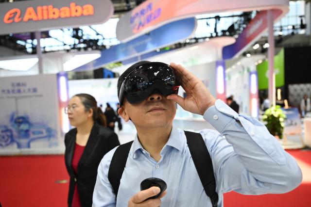 A visitor tests a mixed reality headset at the Qualcomm booth during the China International Supply Chain Expo (CISCE) in Beijing on June 25, 2026. (Photo by Pedro PARDO / AFP)