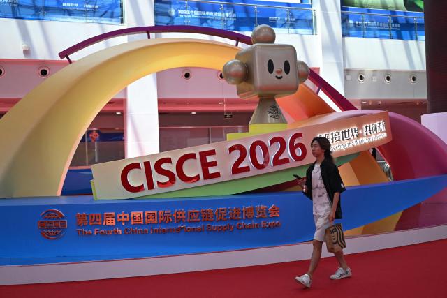 A man walks past an advertisement for the China International Supply Chain Expo (CISCE) in Beijing on June 25, 2026. (Photo by Pedro PARDO / AFP)