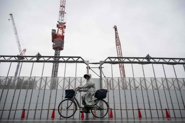 A commuter bikes past a construction site in the rain in Itabashi Ward in north Tokyo, on June 25, 2026. (Photo by ANDREW CABALLERO-REYNOLDS / AFP)