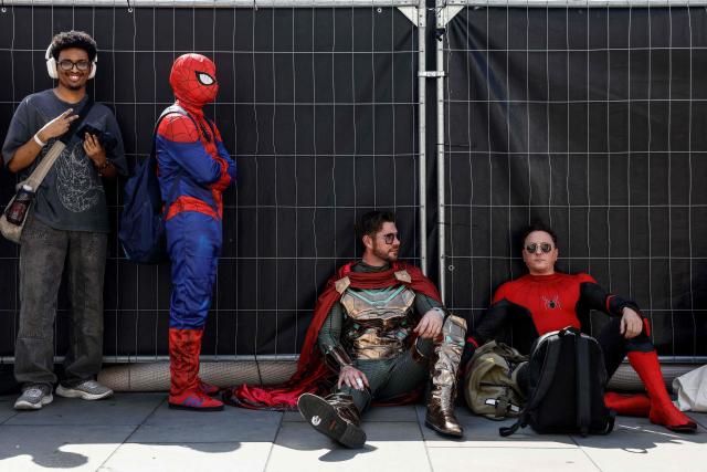 People in costume wait for a promotional event for the upcoming premiere of the film "Spider-Man: Brand New Day", in central London on June 25, 2026. The red carpet photo call event was scaled back due to the extreme heat parts in England this week. (Photo by Brook Mitchell / AFP)